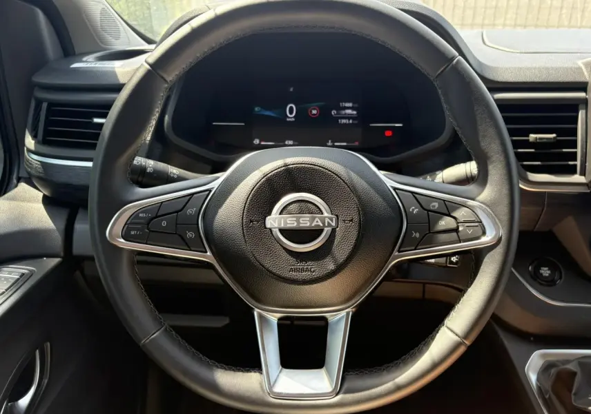 Vue rapprochée du volant noir de la Nissan Primastar Combi 2025 avec tableau de bord numérique et commandes au volant.
