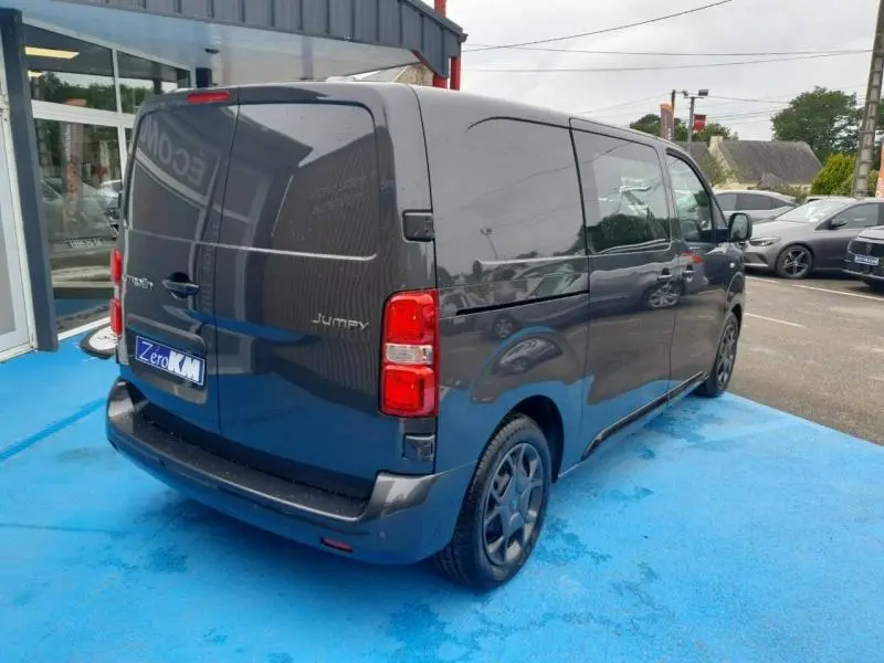 Vue 3/4 arrière droite d’un Citroën Jumpy gris titane métal avec portes arrière battantes et jantes foncées.