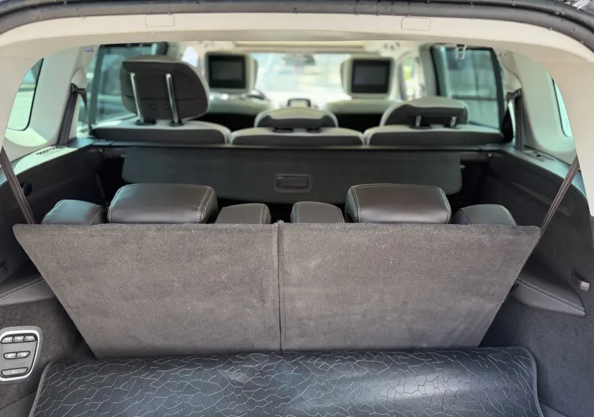 Vue arrière intérieure du coffre du Renault Espace V noir, montrant les sièges en cuir et les écrans intégrés aux appuie-têtes.