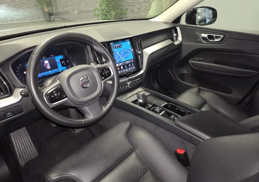 Intérieur noir cuir du Volvo XC60 2023 vu côté conducteur, avec tableau de bord digital et écran tactile central.