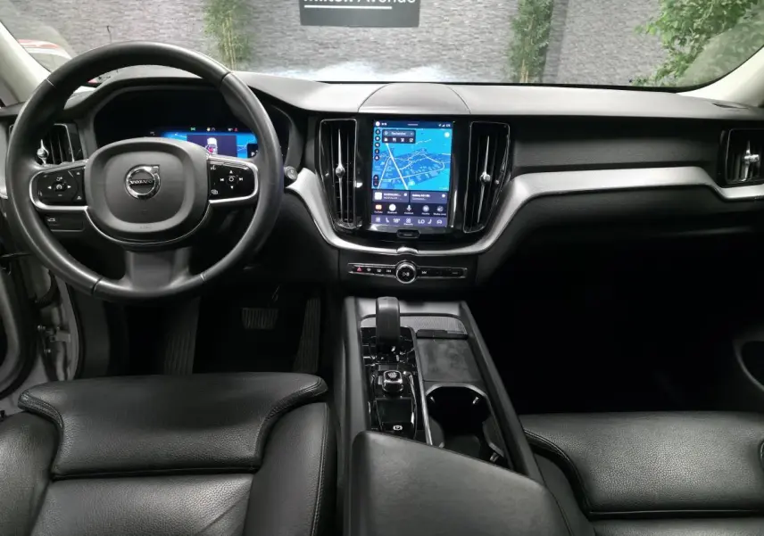 Vue intérieure avant du Volvo XC60 gris, avec tableau de bord digital et écran tactile central lumineux.