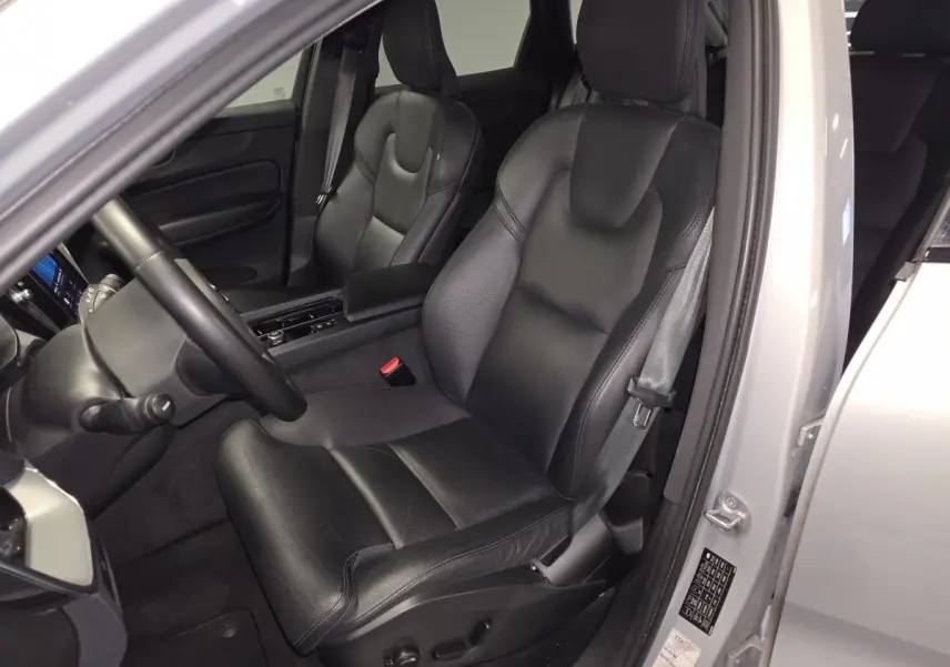 Vue intérieure côté conducteur du Volvo XC60 gris 2023, siège en cuir noir avec accoudoir central.