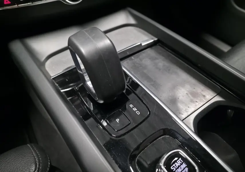 Gros plan sur la console centrale noire avec levier de vitesses automatique et bouton Start/Stop du Volvo XC60 gris.