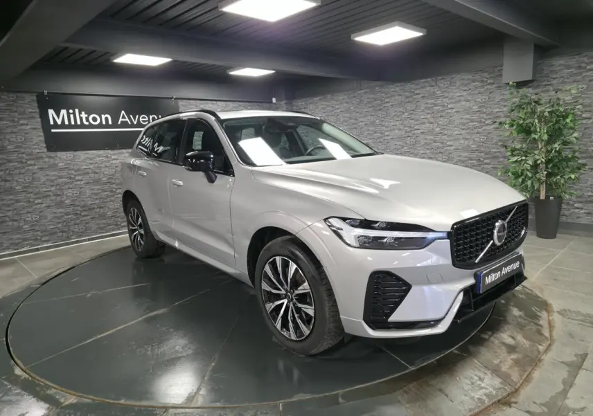 Volvo XC60 gris métallisé en 3/4 avant droit, avec calandre et jantes noires dans un showroom.