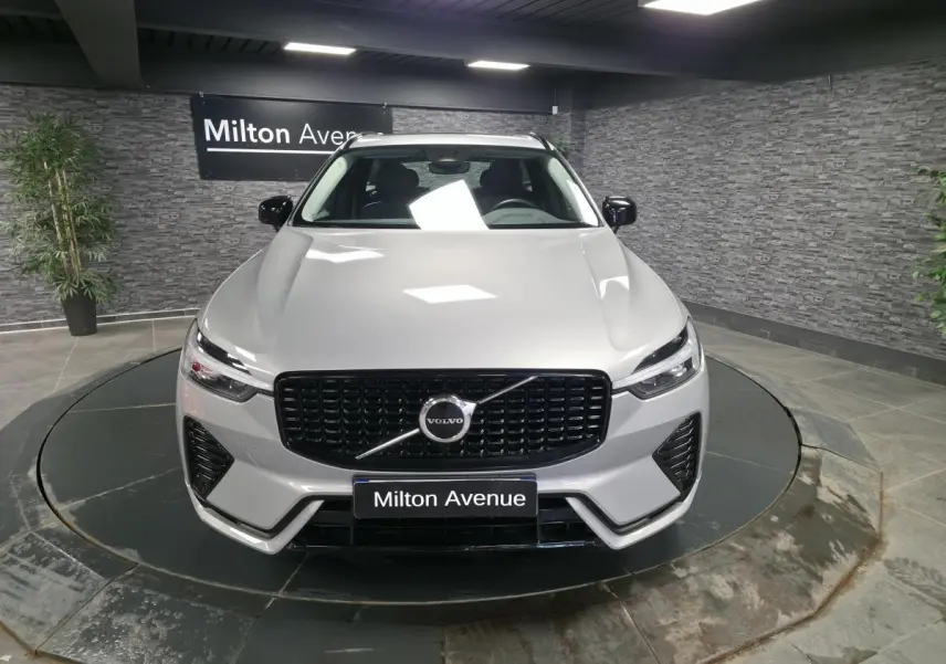 Vue avant d'un Volvo XC60 gris métallisé avec calandre noire laquée et détails noirs sur pare-chocs dans un showroom.