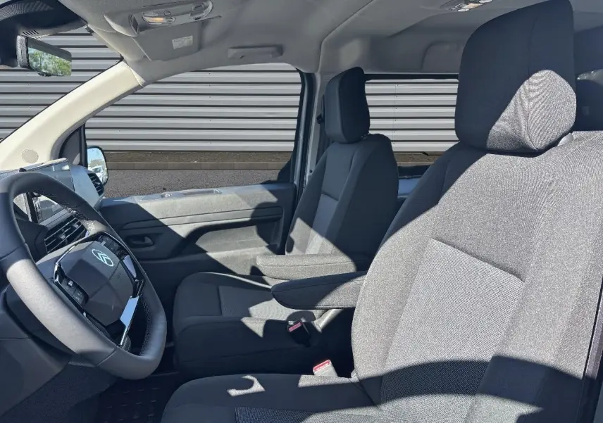 Vue intérieure côté conducteur du Citroën Jumpy gris, montrant les sièges avant et le volant en cuir.