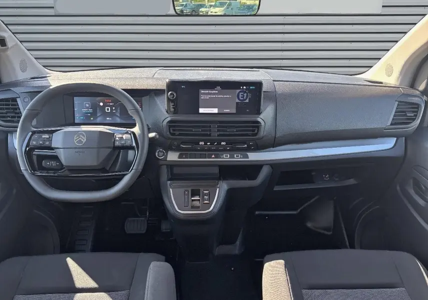 Vue intérieure frontale du tableau de bord du Citroën Jumpy gris Artense, avec volant cuir et écran tactile central.