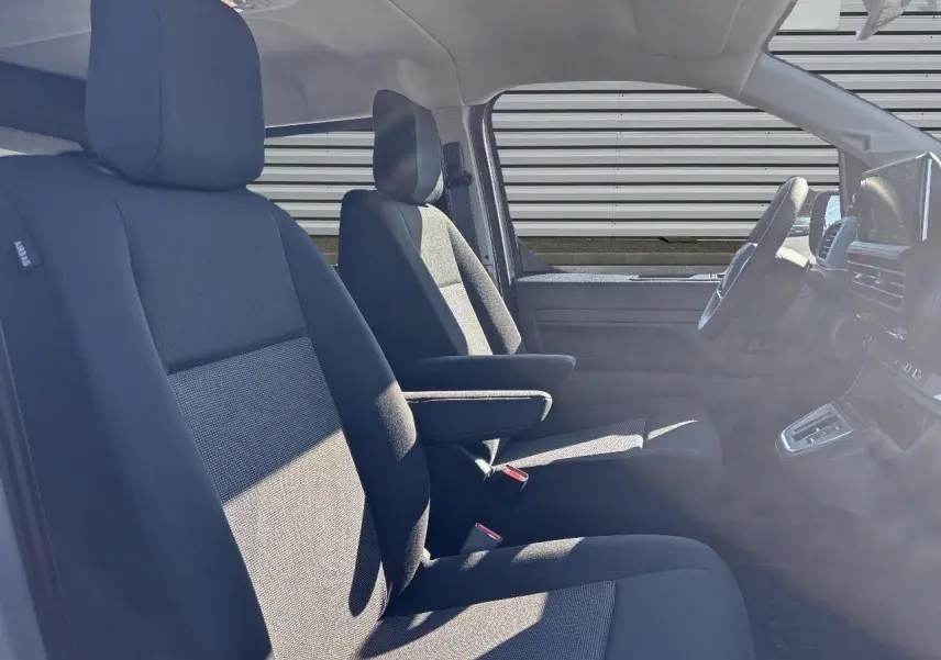 Vue intérieure côté conducteur du Citroën Jumpy gris Artense, montrant les sièges avant avec accoudoir et tableau de bord.