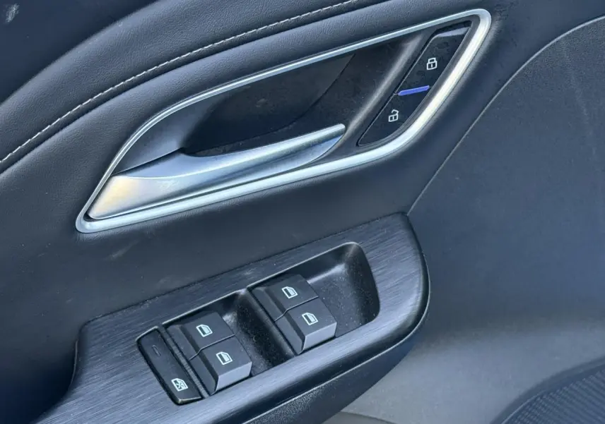 Gros plan sur la porte côté conducteur du MG ZS 1.5 Hybrid+ 197 Luxury 2025, avec commandes de vitres et verrouillage.