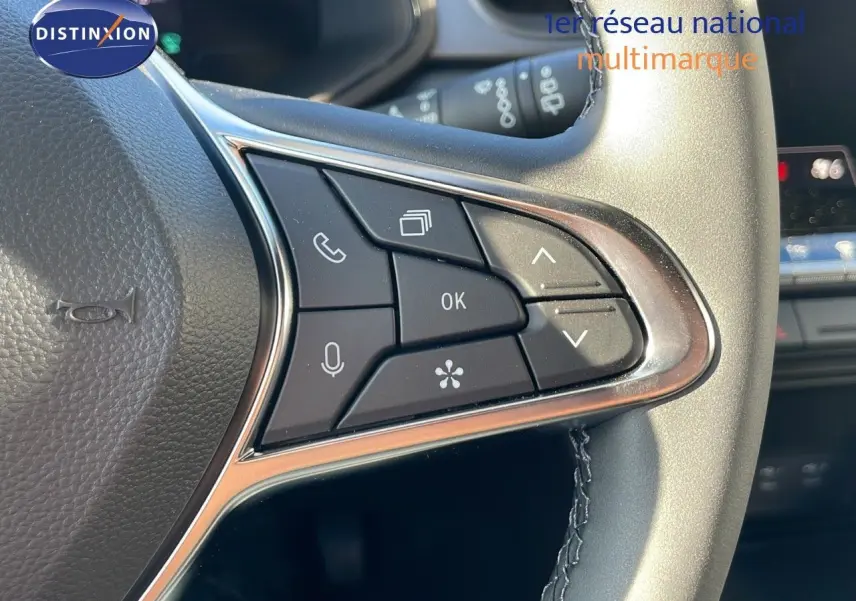 Gros plan sur les commandes multifonctions du volant côté gauche du Renault Captur gris rafale métal avec toit noir.