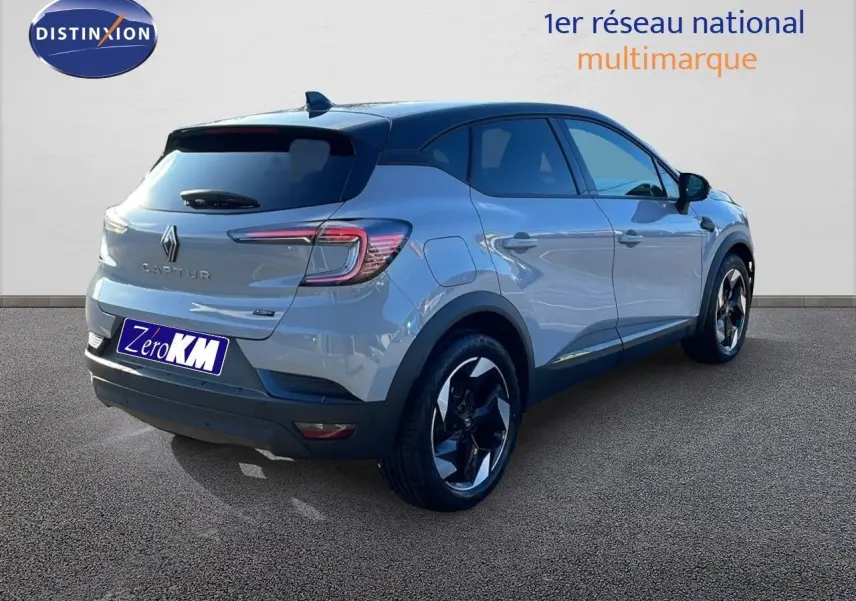 Vue 3/4 arrière droite d'un Renault Captur gris Rafale métal avec toit noir et jantes biton sur fond neutre.