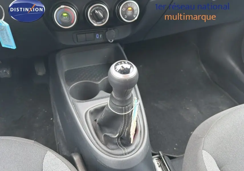 Gros plan sur la console centrale d'une Toyota Aygo X noire 2025, mettant en valeur le levier de vitesse manuel et les commandes de climatisation.