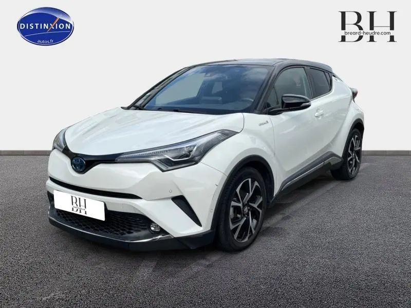 Toyota C-HR 122h Collection blanc nacré bi-ton vu en 3/4 avant droit avec toit noir et jantes alu noires.