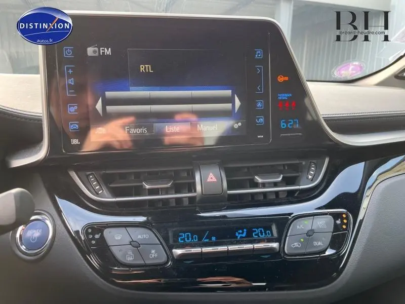 Vue rapprochée de la console centrale du Toyota C-HR blanc nacré, avec écran tactile et commandes climatisation digitales.