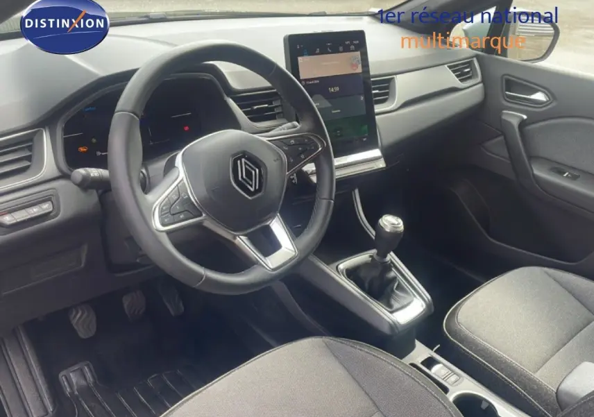 Intérieur avant du Renault Captur 2025, tableau de bord moderne avec écran tactile vertical et levier de vitesse manuel.