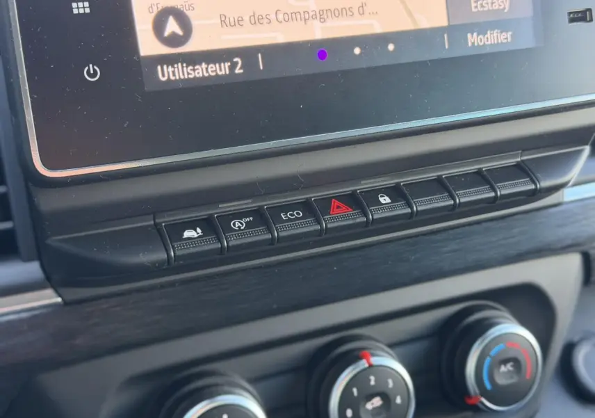 Gros plan sur la console centrale du Nissan Primastar gris, montrant les boutons de commande et l'écran tactile.