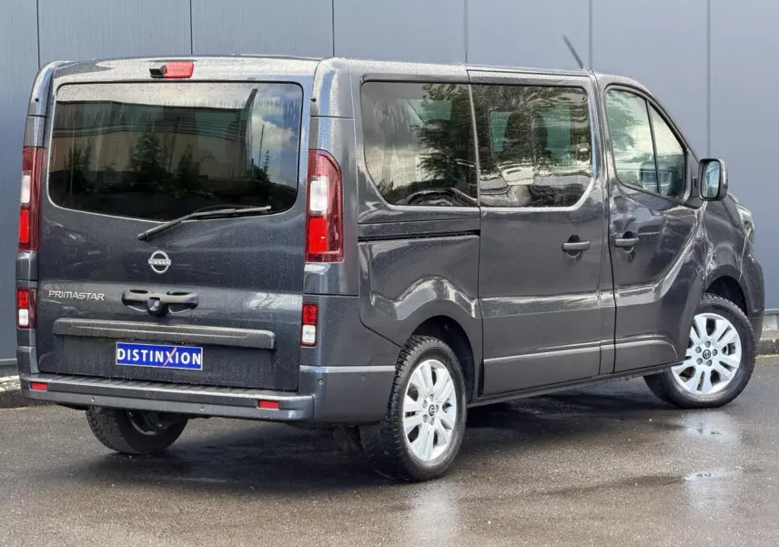 Vue 3/4 arrière droite d'un Nissan Primastar gris Comète avec hayon vitré et jantes alliage 17 pouces.