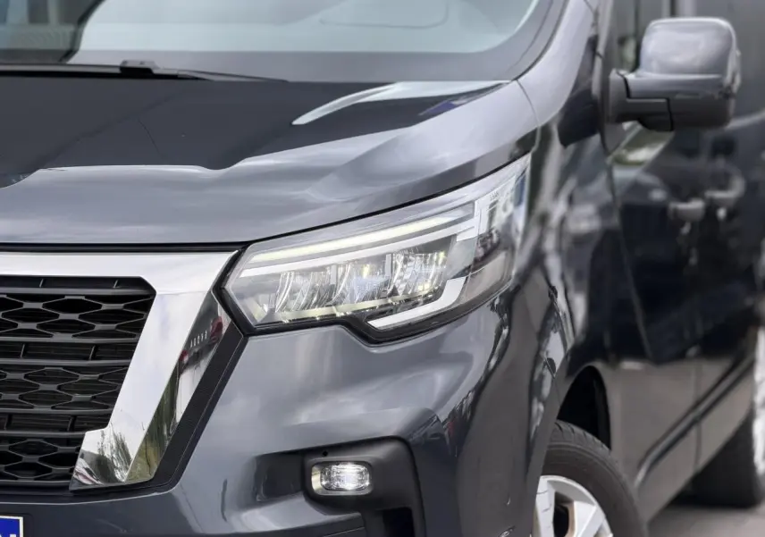 Vue avant droite du Nissan Primastar gris Comète 2025, mettant en valeur les phares LED et la calandre chromée.