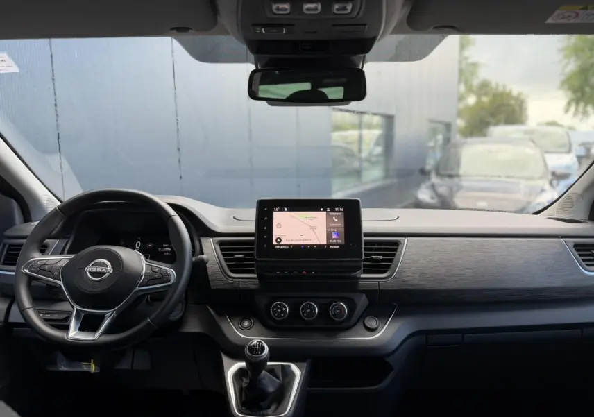 Vue intérieure frontale du tableau de bord du Nissan Primastar gris, avec écran tactile central et volant multifonction.