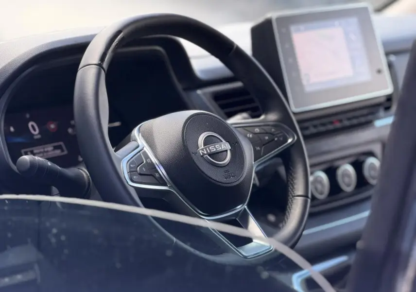 Vue rapprochée du volant noir et du tableau de bord avec écran tactile du Nissan Primastar 2025.
