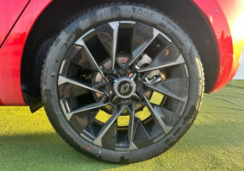 Gros plan sur la jante alliage 17 pouces noire et grise de la Renault Clio V rouge foncé, avec partie arrière visible.