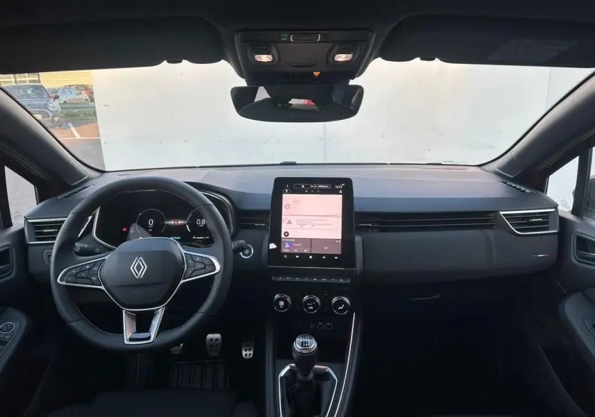 Vue intérieure frontale du tableau de bord de la Renault Clio V rouge foncé, avec volant multifonction et écran tactile vertical.