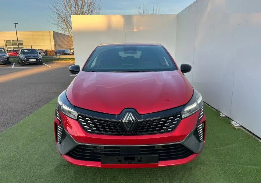 Vue frontale d'une Renault Clio rouge foncé avec calandre noire et feux LED en signature lumineuse verticale.