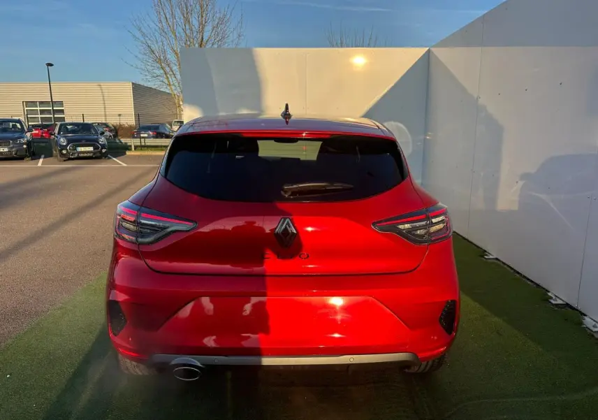 Vue arrière d'une Renault Clio rouge foncé 2025 avec feux arrière LED en forme de C et antenne requin noire.