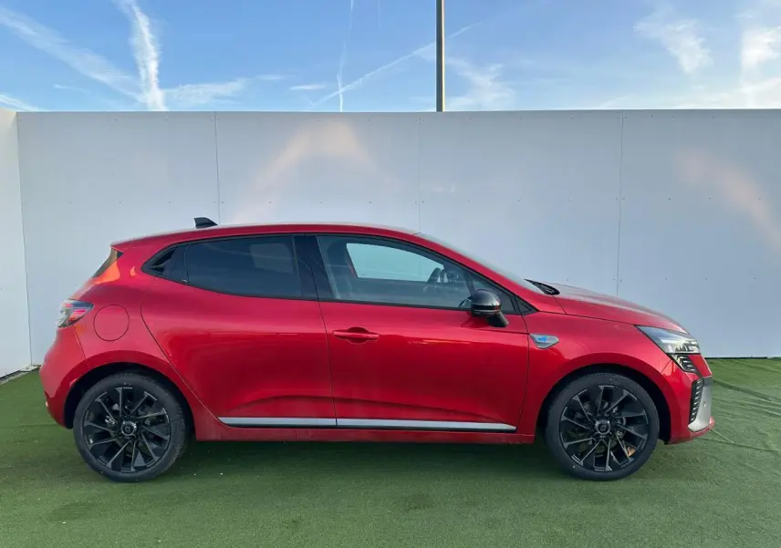Profil droit de la Renault Clio V rouge foncé 2025 avec jantes noires et badges esprit Alpine visibles.