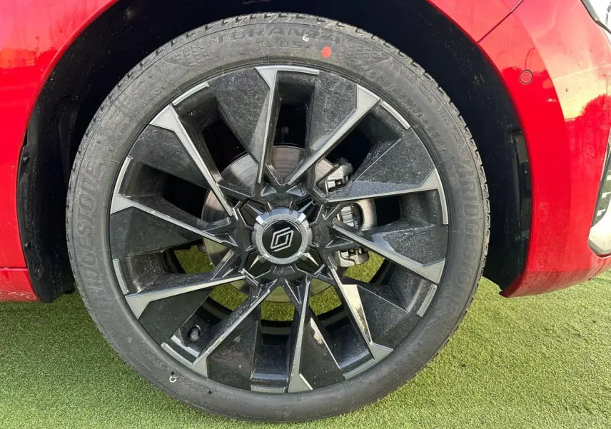 Gros plan sur la jante alliage noire et grise de la Renault Clio rouge foncé, avec logo Alpine au centre.