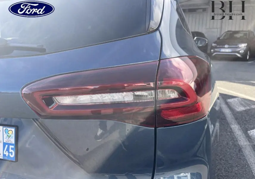 Gros plan sur le feu arrière droit d’une Ford Focus SW 2024 bleu azur métallisé, avec reflet de lumière sur la carrosserie.