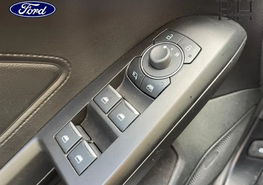 Gros plan sur la commande des vitres et rétroviseurs côté conducteur d'une Ford Focus SW 2024, intérieur noir.