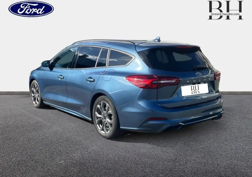 Ford Focus SW bleu azur métallisé vue 3/4 arrière droit, jantes alu et feux arrière LED visibles.