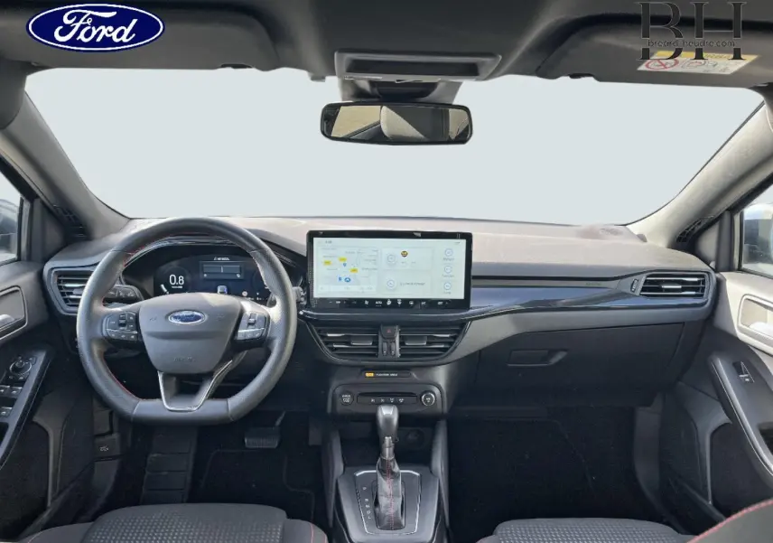 Vue avant de l'habitacle noir de la Ford Focus SW 2024 avec volant cuir, écran tactile central et levier de boîte auto.
