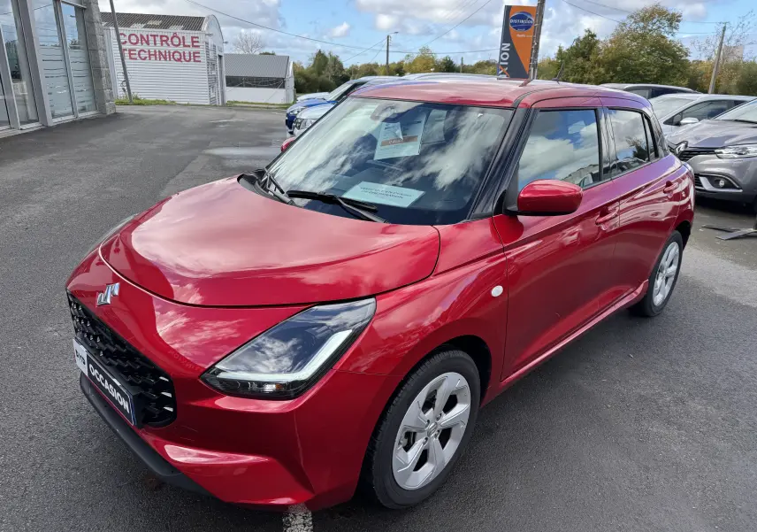 Suzuki Swift 1.2 Hybrid Privilege 2025 en Burning Red Pearl, vue 3/4 avant droit avec calandre noire et jantes argentées.
