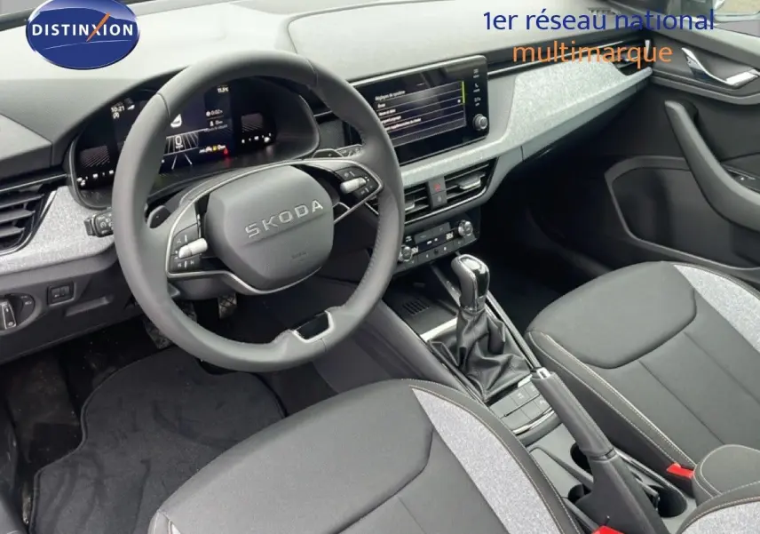 Intérieur de la Skoda Kamiq 2025 vu côté conducteur, tableau de bord moderne et sièges tissu gris noir.