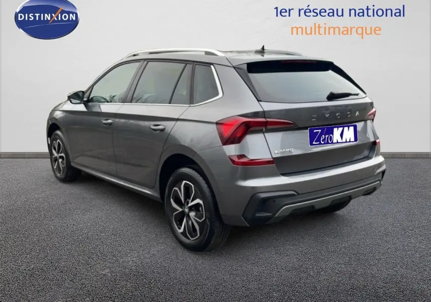 Vue 3/4 arrière droite d'un Skoda Kamiq gris graphite métal avec jantes biton et barres de toit argentées.