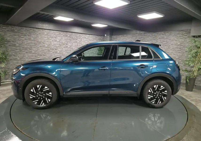 Vue de profil côté gauche d'une FIAT 600 1.2 Hybrid 2024 bleu métallisé avec jantes bicolores et coques de rétroviseurs noires.