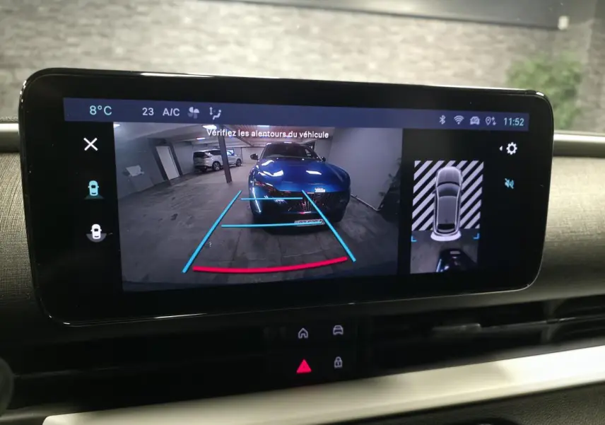 Écran multimédia affichant la caméra de recul et vue 360° d’une FIAT 600 bleu dans un parking intérieur.