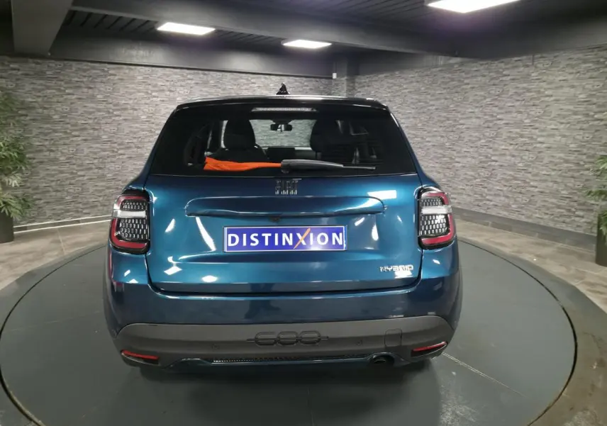 Vue arrière d'une FIAT 600 hybride bleue métallisée avec feux LED et logo Hybrid sur hayon dans un showroom.