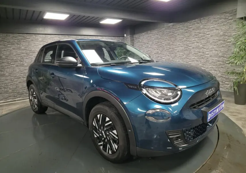 Vue 3/4 avant droit d'une FIAT 600 1.2 Hybrid bleu métallisé avec jantes bicolores et phares LED Infinity.