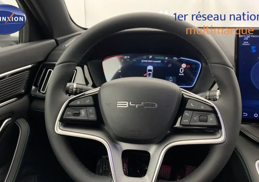 Vue intérieure centrée sur le volant BYD du SEAL U 2025 avec tableau de bord numérique et écran tactile latéral.