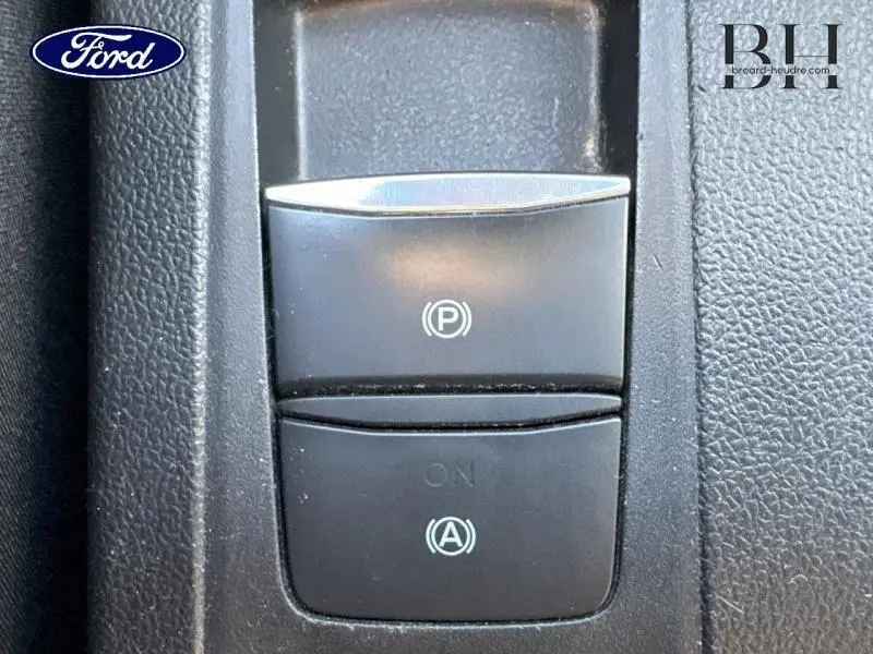 Gros plan sur les boutons du frein à main électrique et de l'arrêt automatique du moteur dans une Ford Focus gris lunaire.