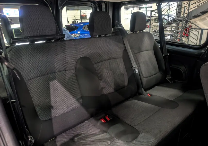 Vue intérieure sur la banquette arrière en tissu gris foncé du Renault Trafic Combi 2023, avec ceintures de sécurité visibles.