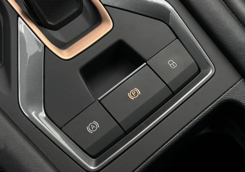 Gros plan sur les commandes de frein à main électronique et verrouillage central dans l’habitacle noir du CUPRA Leon 2025.