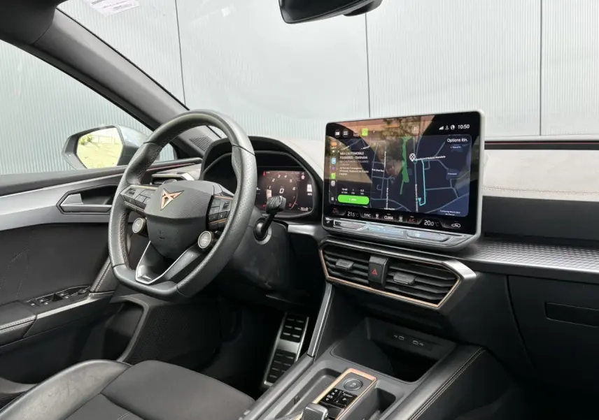 Vue intérieure côté conducteur de la CUPRA Leon 2025, tableau de bord noir avec écran tactile et volant cuir Supersports.