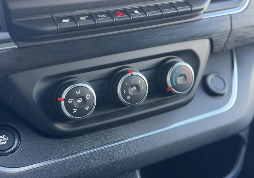 Vue rapprochée des commandes de climatisation et bouton start/stop du Nissan Primastar Combi gris, intérieur noir.
