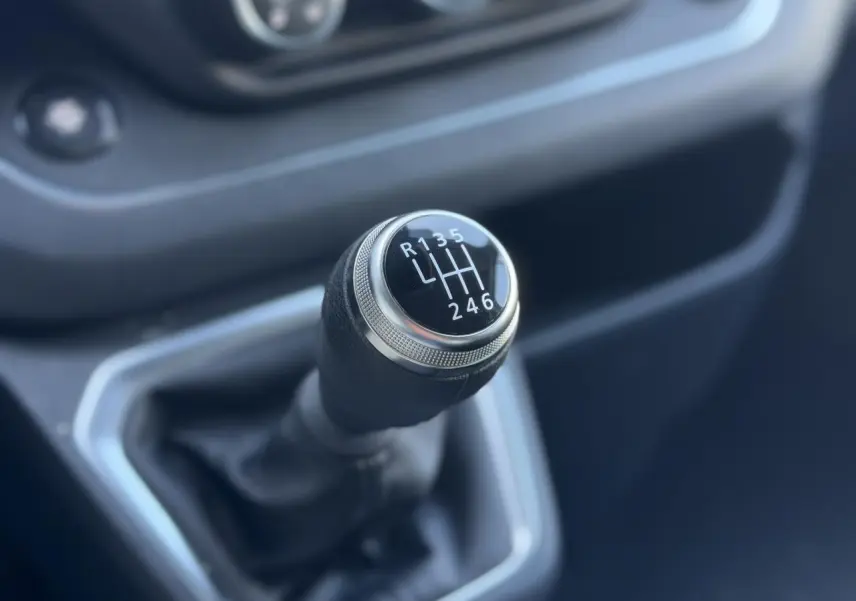 Gros plan sur le levier de vitesses manuel noir du Nissan Primastar Combi 2025, intérieur gris foncé.
