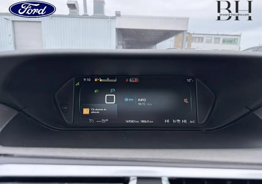 Tableau de bord numérique d'une Citroën C4 Picasso gris Shark, affichant la vitesse et les informations radio.