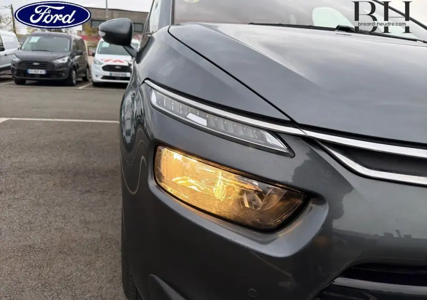 Gros plan sur l'avant droit gris Shark d'une Citroën C4 Picasso 2016 avec feu de jour LED et clignotant allumé.